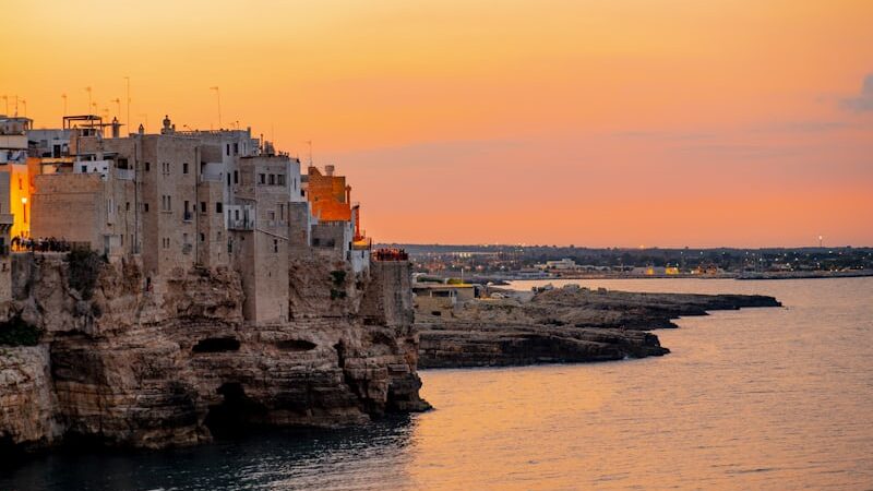 Coastal town in Puglia, Italy, with whitewashed buildings and calm turquoise sea under sunny October skies.